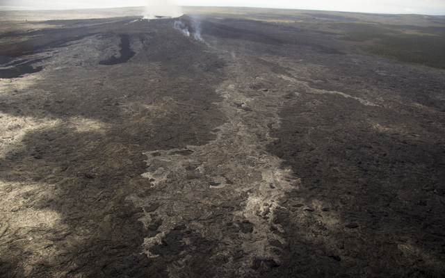 USGS / HAWAIIAN VOLCANO OBSERVATORY                                  Scattered breakouts persist northeast of Puu OO, and the farthest reach of active breakouts was about 3.7 milesfrom the vent on Puu Oo on Dec. 3. A minor change on the flow field occurred, with a breakout from the tube on November 25 that created a small flow that remains active today. This November 25 breakout is easily visible as the lighter colored area extending to the bottom of the photo. The breakout point is visible by the thick fume on the north flank of Puu Oo.