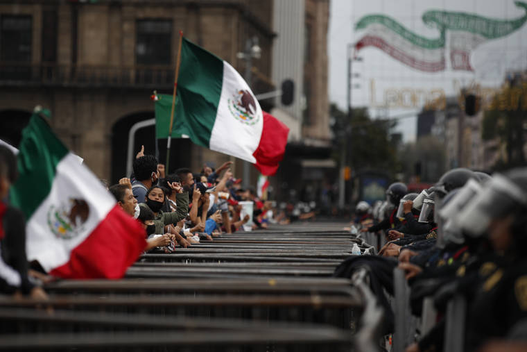 ASSOCIATED PRESS
                                Some participants in a protest marking the sixth anniversary of the forced disappearance of 43 teachers’ college students shout over a barricade and a line of police toward unrelated protesters camping out in Mexico City’s main square to call for the renunciation of the president, Saturday, Sept. 26.