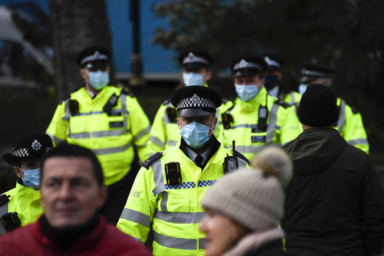 Police officers wear face masks as they patrol an anti-lockdown demonstration in Parliament Square, in London, Monday, Dec. 14, 2020. Britain launched its vaccination program this month after becoming the first country to give emergency approval to the Pfizer-BioNtech vaccine, and authorities plan to dispense 800,000 doses in the first phase. (AP Photo/Alberto Pezzali)