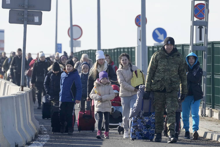 ASSOCIATED PRESS A Polish border guard assists refugees from Ukraine as they arrive to Poland at the Korczowa border crossing today.