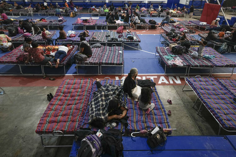 PRENSA ASOCIADA Personas reunidas en el interior de una academia habilitada como refugio para los evacuados de las laderas del volcán de Fuego, que muestra una actividad creciente, en Santa Lucía Cotzumalguapa, Guatemala, hoy.