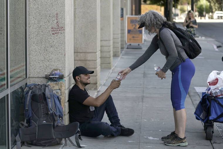 RICH PEDRONCELLI / AP
                                Freddie Ramirez, left, is handed a bottle of water from Kim Burrell, in Sacramento, Calif., Tuesday, Sept. 6.